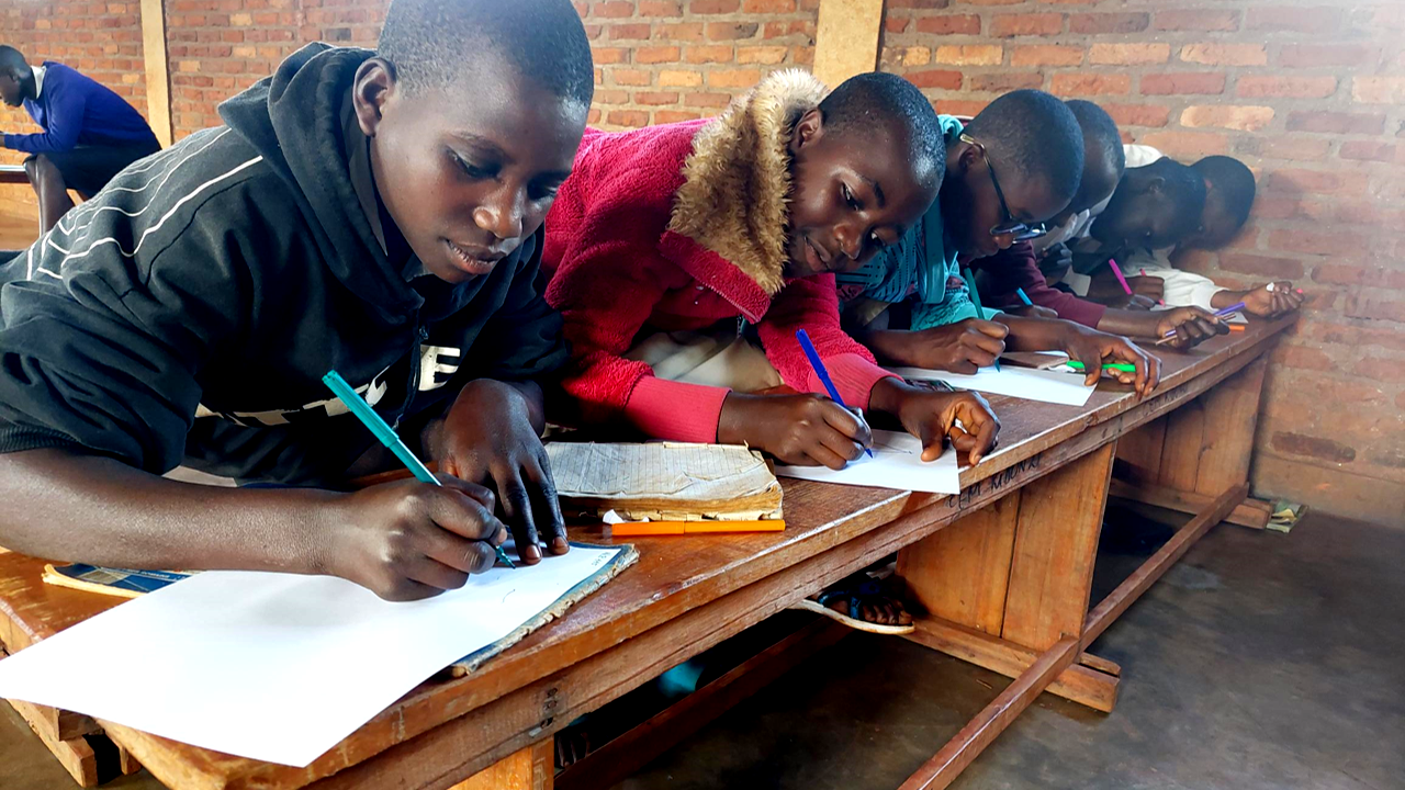 Children in Burundi write at desk